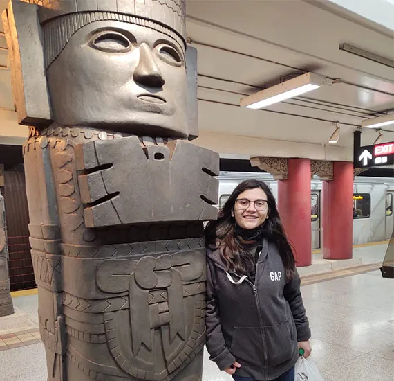 Estudiante participando en actividad de intercambio internacional foto a lado de una estatua