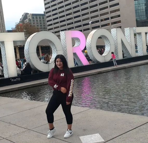 Estudiante enfrente de letrero de toronto en Canadá